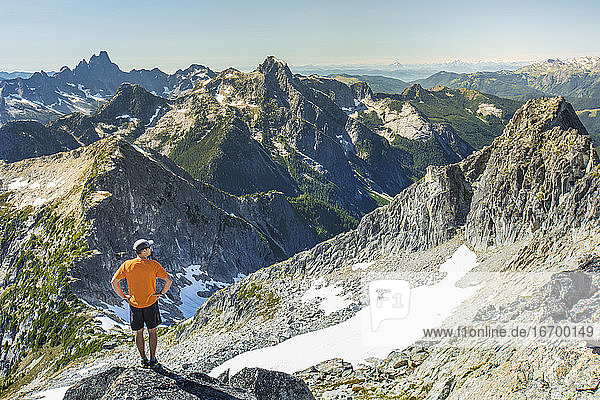 Trail runner looks out at view from the summit of a mountain.