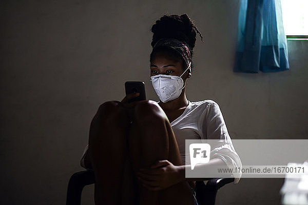 Junge Frau mit Gesichtsmaske und Smartphone