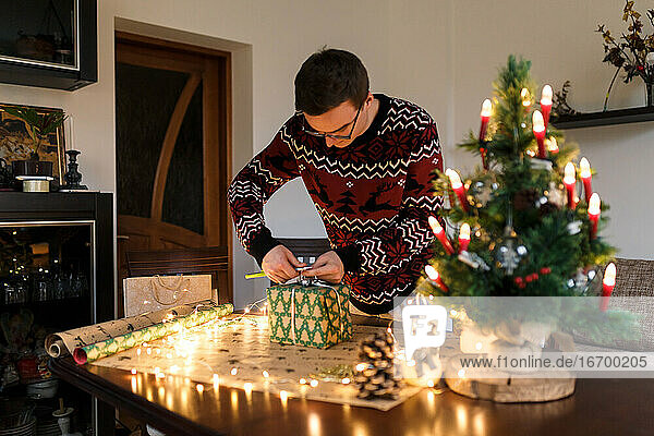 junger Mann packt Weihnachtsgeschenke für Freunde und Familie ein