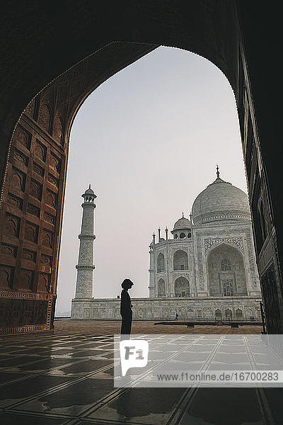 Junge Frau betrachtet das Taj Mahal von der Kau Ban Moschee aus bei Sonnenaufgang  Agra  Indien