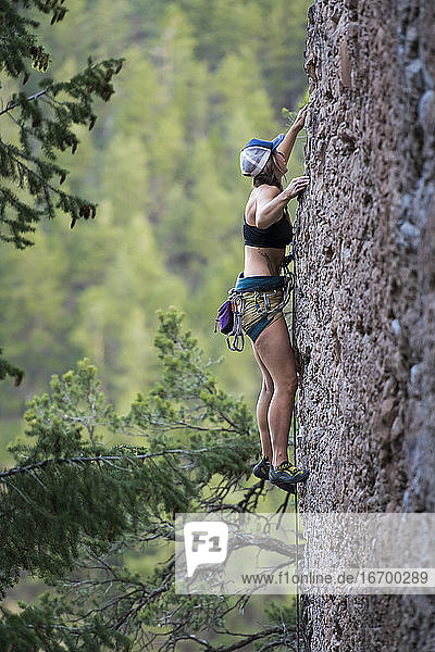 Side view of female hiker climbing rock in forest