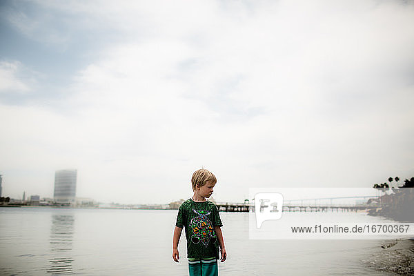 Sechs Jahre alter Junge im Wasser stehend Pier im Hintergrund