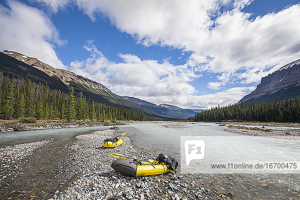 Landschaftlicher Blick auf zwei Packwagen am Flussufer im Banff National Park.