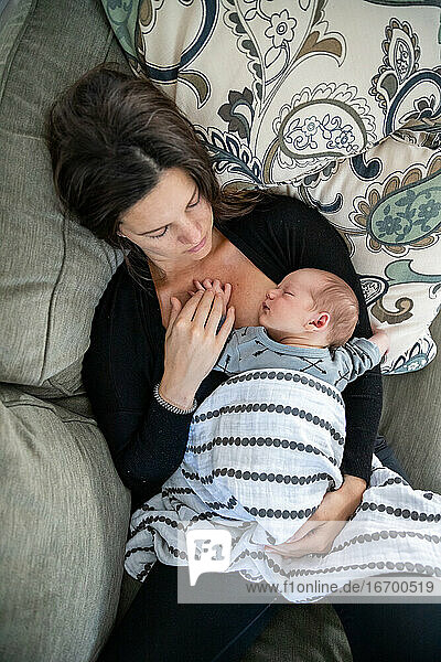Neugeborenes Baby schläft friedlich an der Brust der Mutter.