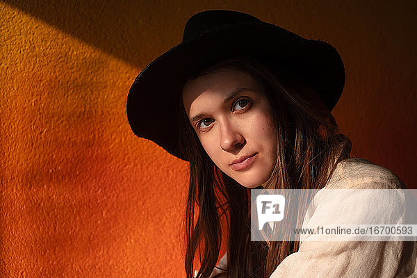 Porträt einer jungen Frau mit Hut  die allein in einem Café sitzt