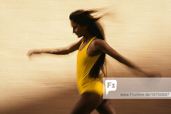 Künstlerische Geschwindigkeitsunschärfe einer jungen Frau  die gegen eine gelbe Wand läuft