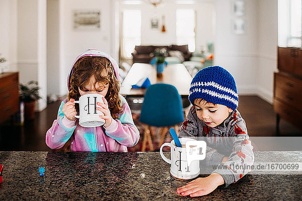 Junge und Mädchen trinken an einem kalten Wintertag drinnen heiße Schokolade
