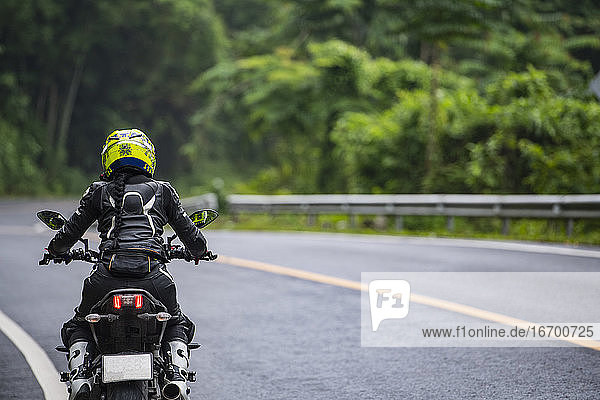 woamn fahren ihr Motorrad auf leeren Autobahn in Thailand
