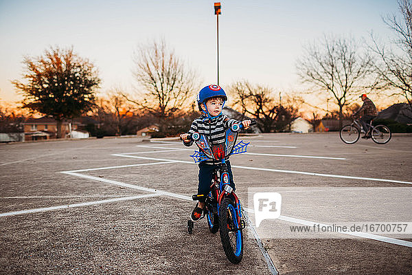 Kleiner Junge sitzt auf einem Fahrrad auf einem Parkplatz und fährt mit seinem Großvater