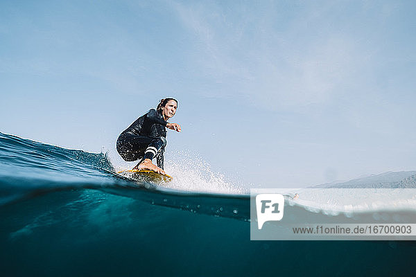 Splitbild einer Surferin im Neoprenanzug beim Surfen auf einem Longboard