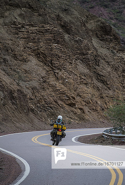 Woman on touring motorbike riding twisting road in Argentina