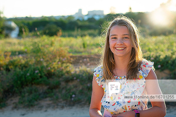 Lächelndes Mädchen im Sommerkleid mit Hintergrundbeleuchtung