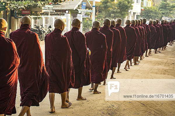 Rückansicht von Mönchen in einer Schlange auf der Straße  die Almosen erhalten  Nyaung U  Myanmar