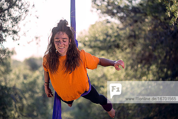 Junges Mädchen  Akrobatin. Übt Seiltanz in der Luft. Frau macht Zirkuskunststücke mit Kleidung im Wald. Balance Hüftschwung.