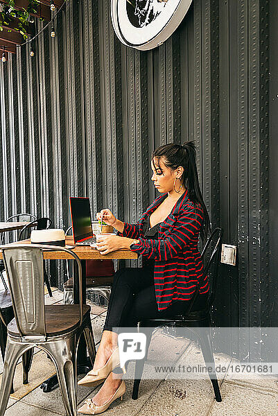 Frau arbeitet auf der Terrasse einer Bar  trinkt einen Kaffee  unternehmungslustige Frau
