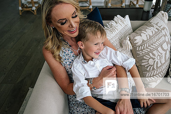 Glückliche Mutter und Sohn kuscheln auf der Couch