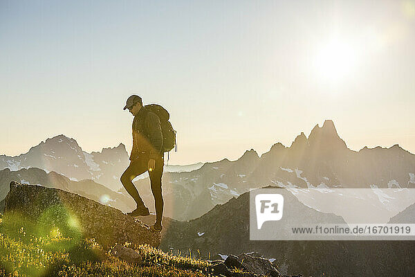 Rucksacktourist wandert auf einem malerischen Bergrücken in Richtung Gipfel.