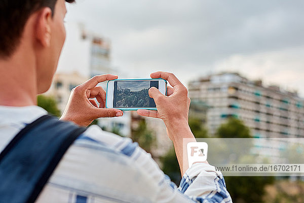 Close-up of a young afro-haired man is taking a photo with his mobile