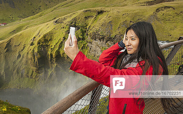 schöne Frau macht Selfie am Skogarfoss-Wasserfall in Island