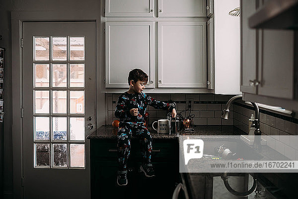 Kleiner Junge in der Küche  der lernt  morgens Kaffee zu kochen