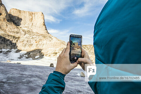 Ein Bergsteiger fotografiert den Berg Asgard mit seinem Handy.