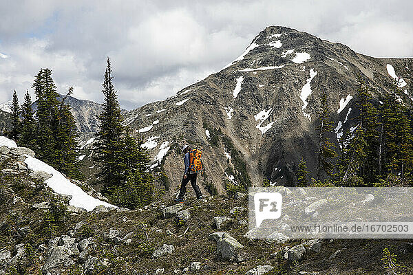 Wanderer erkundet bewaldete Berge und wandert vor einem felsigen Abhang