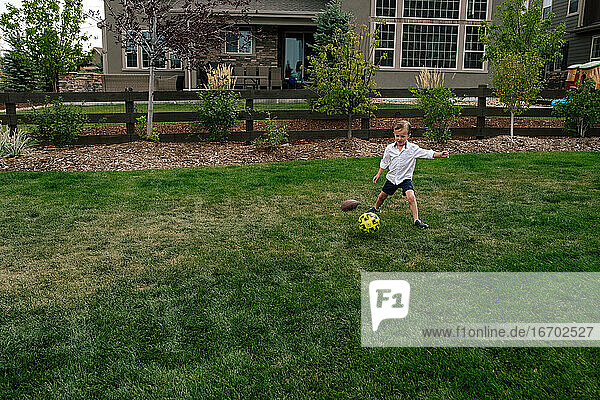 Kleiner Junge kickt einen Fußball im Hinterhof