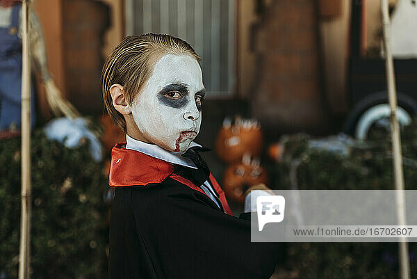 Young boy dressed as Dracula posing in costume at Halloween