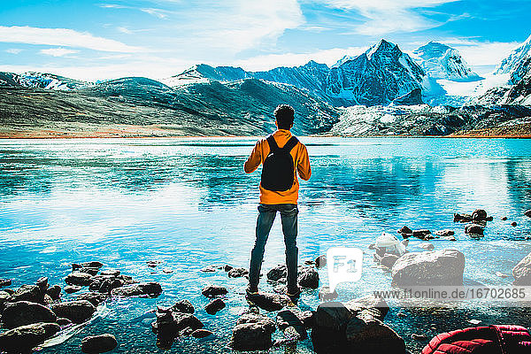 Mann steht auf einem schneebedeckten Berg mit See