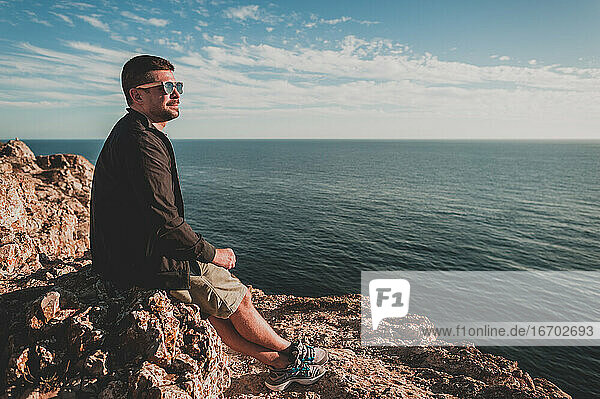 Young man looking out over ocean at sunset in Portugal in summer