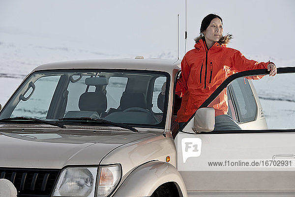 Frau  die in der Tür ihres Geländewagens in Island steht