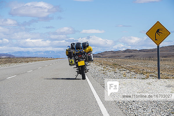 Abenteuermotorrad neben einem Windwarnschild in Argentinien geparkt