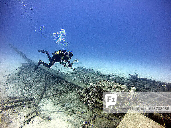 Underwater diving photographer taking pictures over an old wreck