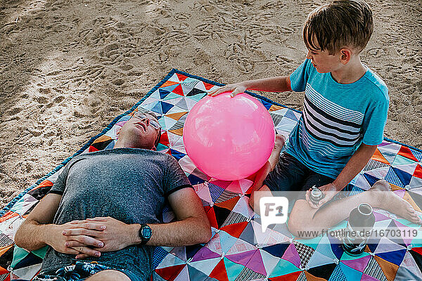 Vater und Sohn entspannen sich auf einer Picknickdecke an einem sonnigen Tag