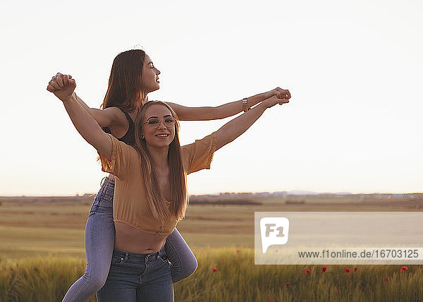 two women holding hands at sunset in the field
