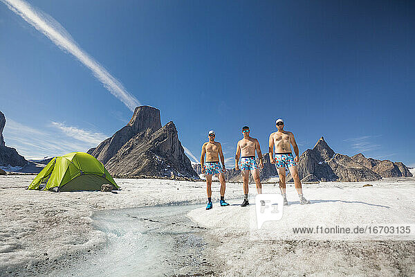 Drei Bergsteiger  die nur mit Unterwäsche bekleidet sind  stehen auf einem Gletscher.