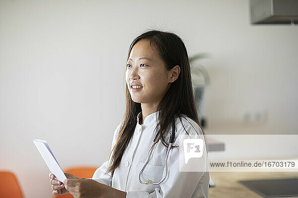 junge asiatische Ärztin mit Bericht in einer Praxis