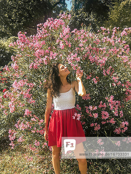 Mädchen im roten Kleid riecht an rosa Blumen