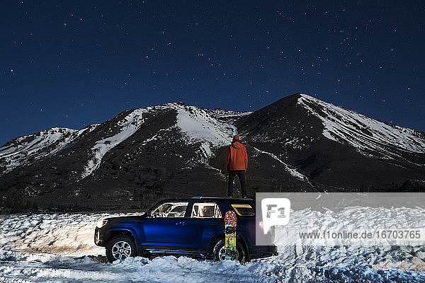 Rückansicht eines Geländewagens gegen einen Berg im Winter bei Nacht