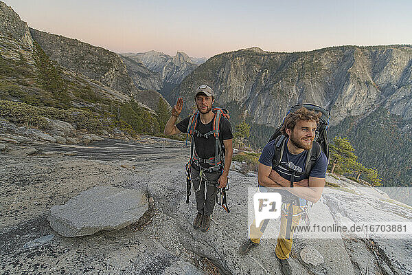 Two hikers at the top of El Capitan in Yosemite Valley at sunset
