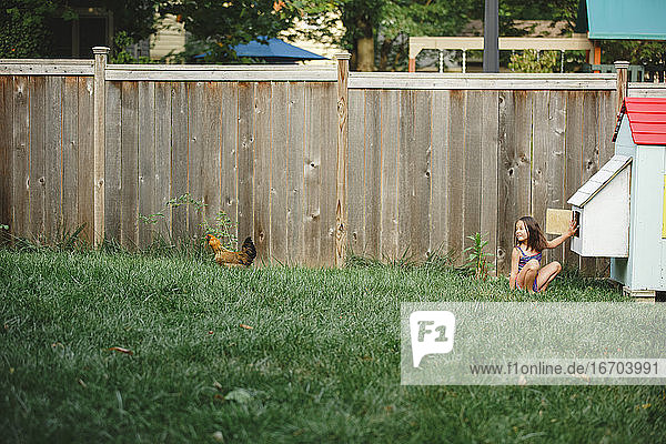 Ein lächelndes Kind spielt im Sommer mit seinem Huhn im Hinterhof