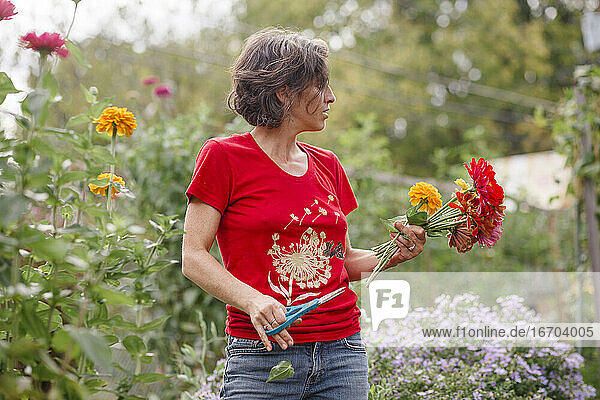 Eine Frau steht mit einem Blumenstrauß aus Wildblumen in einem schönen Garten