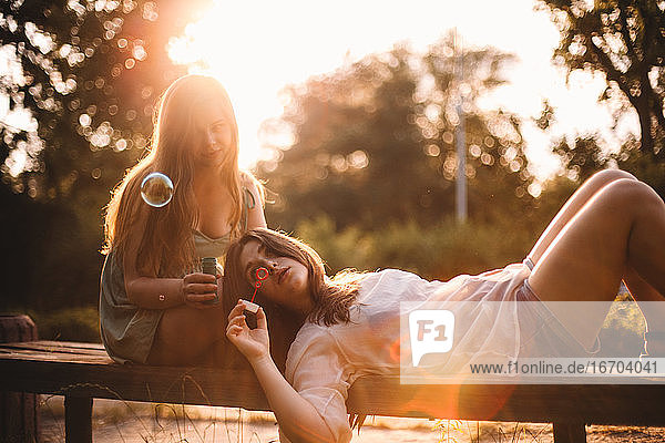 Lesbisches Paar spielt mit Blasen beim Entspannen im Park im Sommer