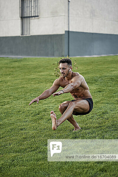 Ein Mann ohne Hemd macht harte Gymnastik auf dem Rasen