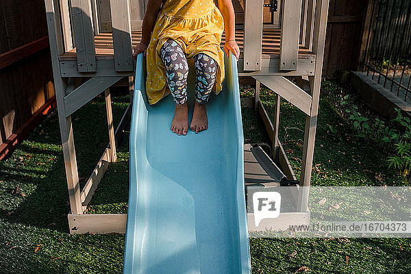 Kind auf der Spitze einer blauen Rutsche sitzend