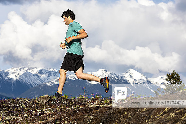 Man trail runs on a scenic alpine mountain trail in British Columbia.
