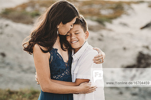 Liebevolle Mutter umarmt lächelnden Teenager-Sohn