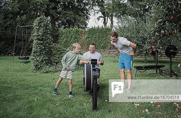 zwei Männer und ihr Sohn trainieren in ihrem Heim-Fitnessstudio im Garten