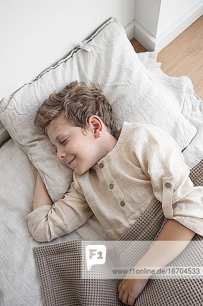 Junge in Hauskleidung Süße Träume in natürlicher Bettwäsche.