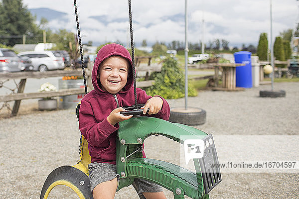 Junge sitzt auf einem Traktor auf dem Bauernhof  der aus recycelten Reifen hergestellt wurde